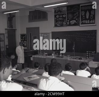 Anni '60, storico, arabo maschio in piedi davanti a una lavagna, insegnando scolari in una classe, con bianco-rivestito assistente maschile in presenza, Jeddah, Arabia Saudita. Foto Stock