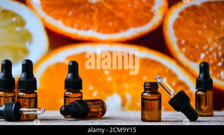 Bottiglia di olio essenziale dalle arance su sfondo di legno con pezzi di arance - medicina alternativa. Olio aromatico essenziale con arance. Foto Stock