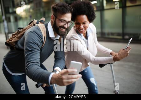 Imprenditori felici che utilizzano dispositivi tecnologici gadget vicino alla parete di un edificio moderno Foto Stock