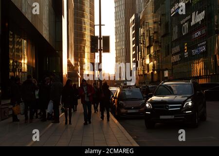 Mosca, Russia, 21 febbraio 2020: La gente cammina lungo una strada a Mosca Сity con la luce brillante del tramonto che splende tra gli edifici. Foto Stock