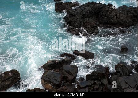 Atmosfera Moody con onde frose che si infrangono sulle rocce vulcaniche nere, a Puerto de la Cruz, Tenerife, Isole Canarie, Spagna, arrabbiato oceano da vicino Foto Stock