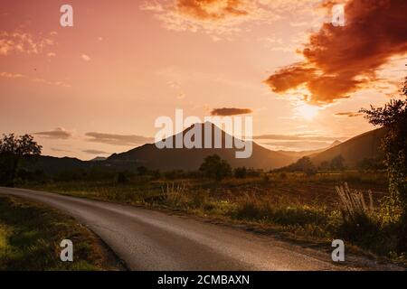 Incredibile paesaggio di montagna con tramonti vibranti e strada di campagna, sfondo di viaggio Foto Stock