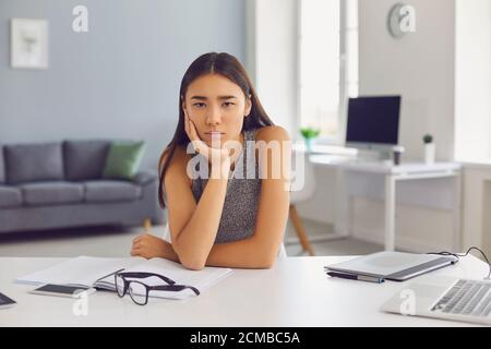 Triste ragazza asiatica esaurisce le idee e soffre da crisi creativa incapace di scrivere un buon saggio Foto Stock