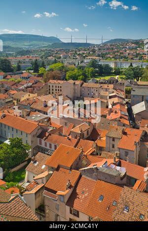 Vista giù sui tetti di tegole rosse dal Belfry a Millau città, con il Viadotto Millau in lontananza, Aveyron, Francia Foto Stock