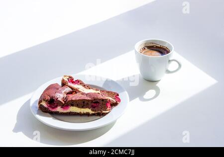 Tazza di caffè e torta brownie fatta in casa con formaggio casolare e ciliegie sul tavolo. Colazione al mattino soleggiato. Foto Stock