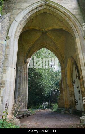 Percorso che conduce attraverso un arco di una cappella medievale nel vecchio cimitero con la bicicletta sullo sfondo Foto Stock