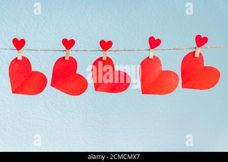 Cuori d'amore appesi sulla corda su uno sfondo blu Foto Stock