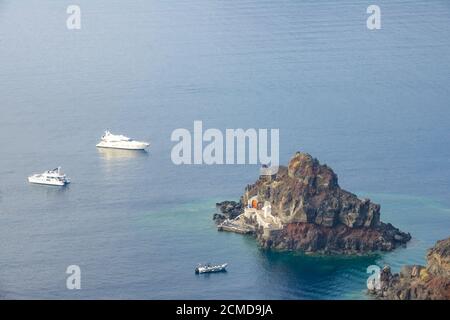 Vista dall'alto su una piccola isola rocciosa con un molo. Due yacht e una barca a motore da diporto ancorati nelle vicinanze Foto Stock