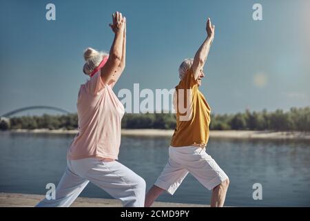Sorridendo yogi femmina e il suo sposo anziano che pratica insieme Foto Stock