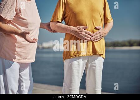 Uomo caucasico anziano che tiene lo stomaco con entrambe le mani Foto Stock