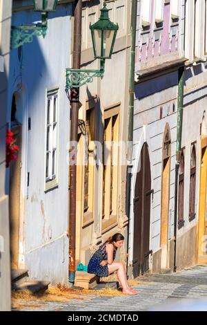 una ragazza che siede a due passi di casa nel centro storico Di Praga Foto Stock