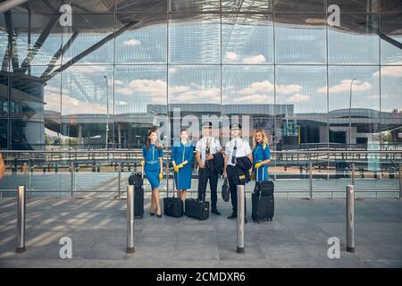 Lavoratori delle compagnie aeree con valigie di viaggio in piedi per strada Foto Stock