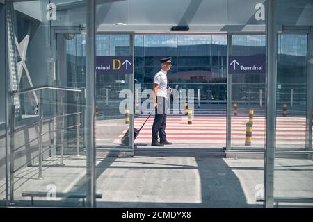 Bel pilota di sesso maschile in piedi fuori dal terminal dell'aeroporto Foto Stock