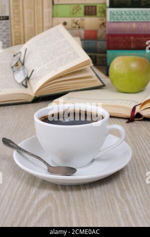 Una tazza di fragranti caffè nero sul tavolo contro lo sfondo di un libro aperto Foto Stock