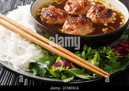Il culo è un piatto vietnamita di maiale alla griglia, noodle e erba chioccia nel piatto sul tavolo. Orizzontale Foto Stock