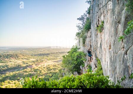 Uomo che arrampica una roccia con attrezzatura in Portogallo Foto Stock