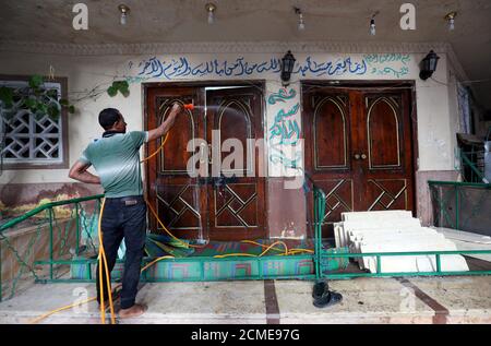 Un volontario spruzzi disinfettante fuori di una moschea come è preparato per la preghiera dopo essere stato riaperto, a seguito dello scoppio della malattia del coronavirus (COVID-19), al Cairo, Egitto, 26 giugno 2020. REUTERS/Mohamed Abd El Ghany