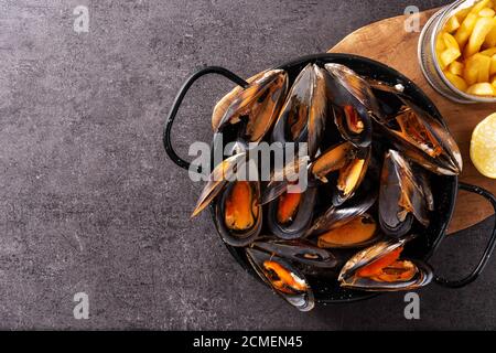 Mouscoels e patatine fritte o melues-frites su ardesia nera. Tipica cucina belga. Foto Stock