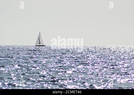 barca a vela su un oceano scintillante Foto Stock