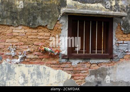 Georgetown, Penang, Malesia - 18 aprile 2016: Un vecchio muro di mattoni con finestra di legno Foto Stock
