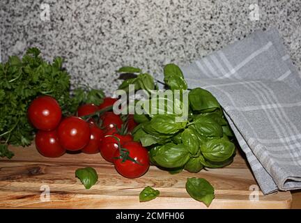 Verdure fresche e colorate su un tagliere di legno con un asciugamano rustico da cucina leggermente drappeggiato sul lato Foto Stock