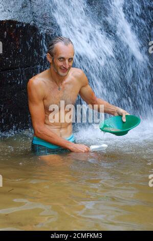 prospector che ansimano l'oro in un fiume con scatola chiusa cascata Foto Stock