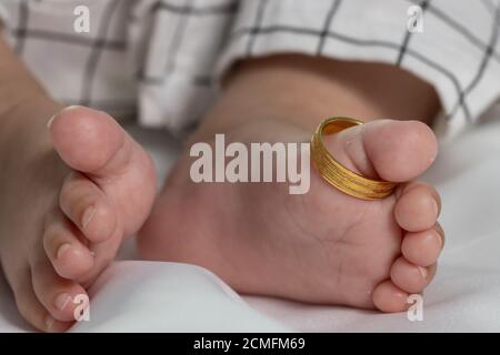 Anelli di nozze sulle gambe piccole di un bambino neonato. Foto Stock