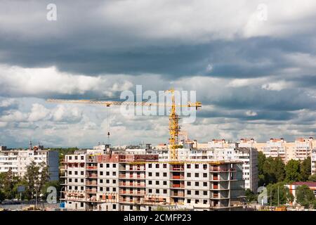 Gru di costruzione in cantiere in città su cielo nuvoloso sfondo Foto Stock