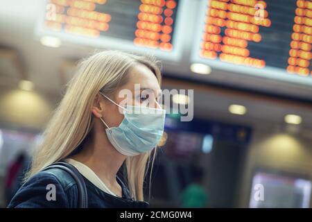 donna che indossa una maschera protettiva sulla stazione ferroviaria affollata durante pandemia virale Foto Stock