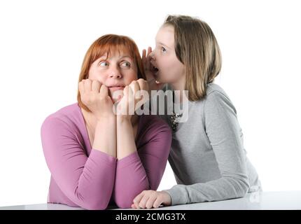 La ragazza dice con entusiasmo qualcosa nell'orecchio di sua madre. Foto Stock