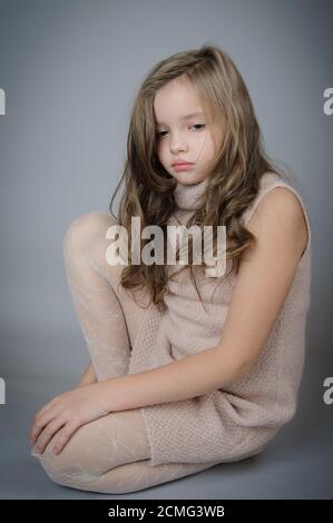 Ritratto di una ragazza piuttosto triste che è seduta sul pavimento. Foto Stock