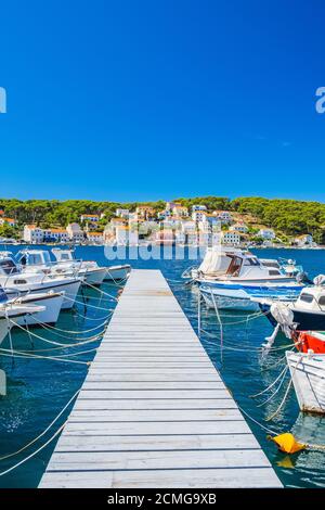 Città di Lussinpiccolo sull'isola di Lussino, costa adriatica in Croazia, barche su banchine e vecchie case in background Foto Stock