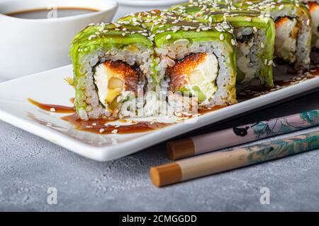 Sushi Imposta nigiri, Uramaki, California, Philadelphia, su un piatto bianco. Zenzero e wasabi nelle vicinanze. Salsa di soia in un recipiente bianco. Su uno sfondo grigio chiaro Foto Stock