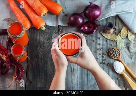 Ferro da stiro la tazza con il succo di carota in mani femminili Foto Stock