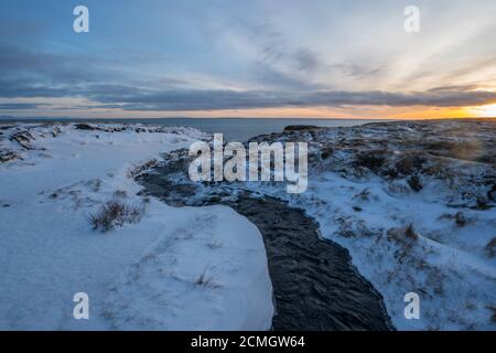 Fiume ghiacciato che scorre verso il mare in Islanda Foto Stock