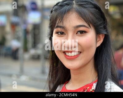 Giovane donna vietnamita con occhi bellissimi e rossetto rosso sorride per la macchina fotografica. Foto Stock