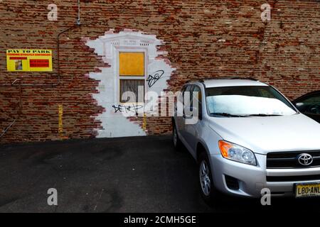 L'auto Toyota parcheggiata accanto all'imbarco 'paga qui in anticipo' finestra in muro di vecchio edificio in mattoni vicino al parcheggio auto, Baltimora, Maryland, USA Foto Stock