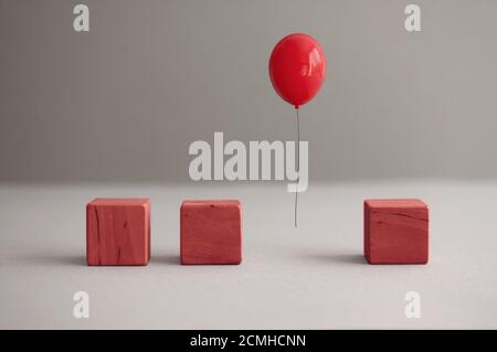 Palloncino rosso a mezz'aria tra cubetti quadrati di legno Foto Stock