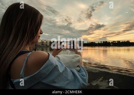 la giovane donna scatta una foto di un bellissimo tramonto sullo stagno Foto Stock