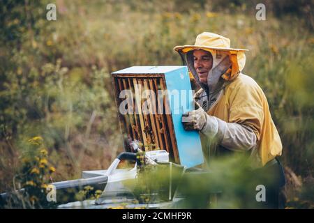 Ritratto di un apicoltore in abbigliamento protettivo che lavora con l'attrezzatura per affumicatori di api. Concetto di apicoltura, spazio di copia Foto Stock