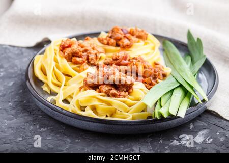 Tagliatelle bolognese con carne tritata su fondo nero in cemento. Vista laterale, primo piano. Foto Stock