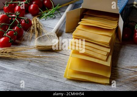 fogli di lasagna grezzi, non cotti, essiccati su tavola di legno con decorazione italiana Foto Stock