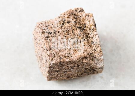 primo piano di un campione di minerale naturale proveniente dalla raccolta geologica - Roccia di Aplite non lucidata su sfondo di marmo bianco Foto Stock