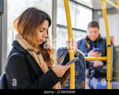 Mosca. Russia. 16 settembre 2020. Una giovane ragazza dai capelli scuri si alza sull'autobus con uno smartphone in mano e si tiene su un corrimano. La ragazza Foto Stock