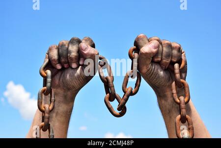 Due mani maschili che tengono una catena metallica arrugginita Foto Stock