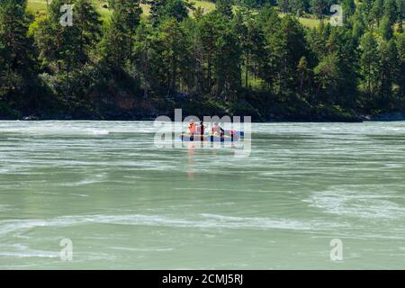 Gruppo di turisti che riposano ad Altai e che rafting in montagna fiume - Katuni turchese su gomma gonfiabile blu barca in speciale protezione gialla ves Foto Stock