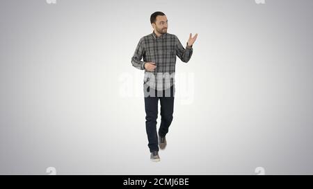 Giovane uomo sicuro in camicia e jeans che cammina verso la macchina fotografica an Foto Stock
