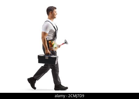 Immagine di un riparatore in uniforme con profilo a lunghezza intera camminare e trasportare un martello e una cassetta degli attrezzi isolati su sfondo bianco Foto Stock