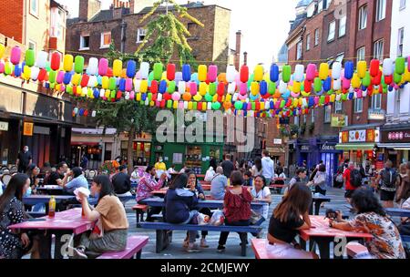 I tavoli da picnic sono pieni di turisti sotto le colorate lanterne arcobaleno al sole mentre illuminano le strade di Chinatown. Chinatown London, in collaborazione con la London Chinatown Chinese Association (LCCA), ha sostituito le iconiche lanterne rosse dell'area con migliaia di lanterne speciali colorate dell'arcobaleno. Le file di lanterne dai colori vivaci per le strade di Chinatown fanno parte della campagna LoveChinatown, per sostenere la comunità delle aziende di Chinatown e dare il benvenuto sicuro alle persone che tornano nella zona. L'arcobaleno è stato anche un simbolo di sostegno per tutta la pandemia a Foto Stock
