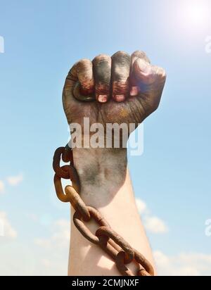 la mano dell'uomo è racchiusa in una catena arrugginita di ferro Foto Stock